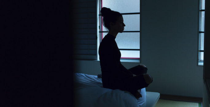 Kvinna sitter med korsade ben på en säng