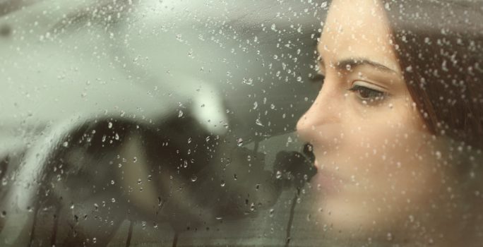 Deprimerad kvinnan tittar ut genom bilfönster