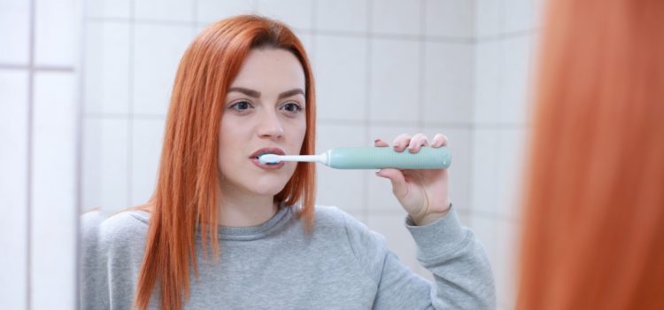 Kvinna borstar tänderna med en eltandborste